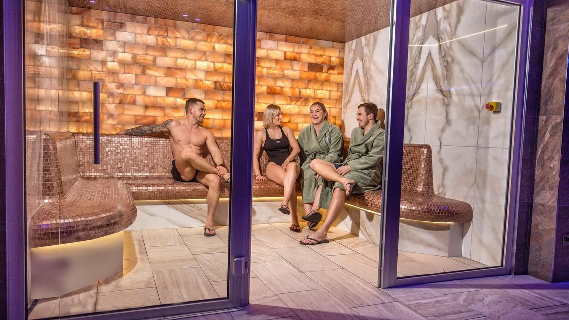 Luxury salt steam room at The Quay featuring illuminated Himalayan salt walls, mosaic seating and ambient spa lighting.