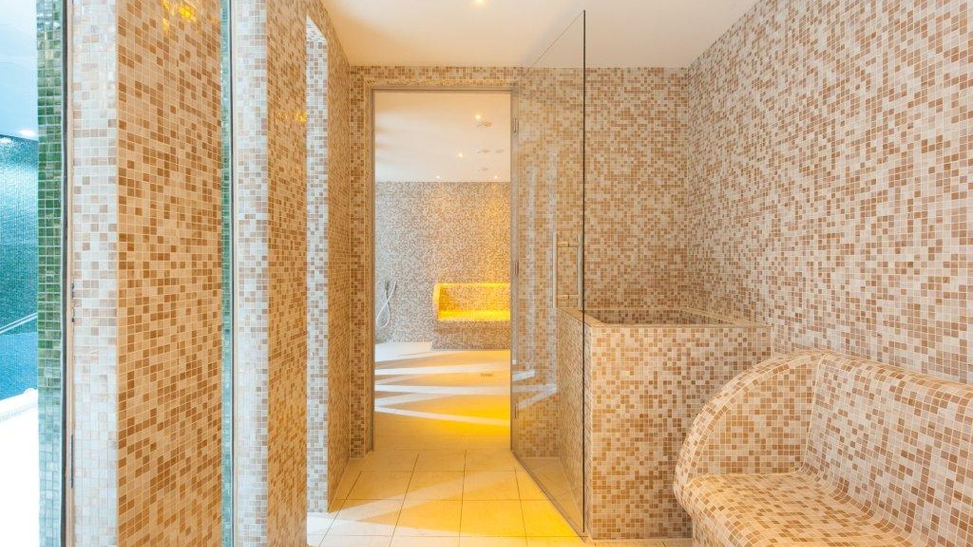 Contemporary mosaic steam room at Westminster Lodge with heated seating, glass partitions and atmospheric lighting.